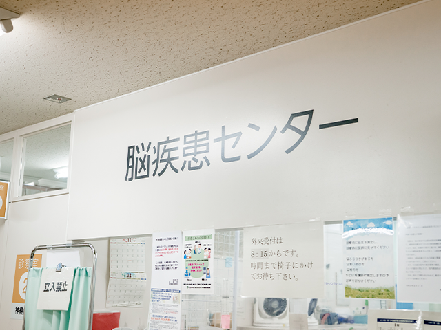 脳疾患センターの壁に掲示された看板と周囲の案内ポスターが写っている画像。