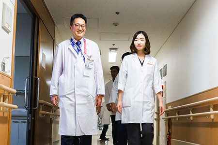 大学病院の廊下を歩く医師と看護師の姿、専門的な医療現場の雰囲気を表現。