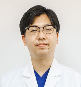 病院助手の卯月大さんが白衣を着て微笑んでいるポートレート。