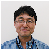 臨床教授の野地秀義氏が微笑んでいるポートレート。背景はシンプルな白色。