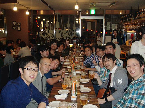 合同歓迎会の様子を写した写真。テーブルには飲み物や料理が並び、参加者たちが笑顔でポーズをとっている。
