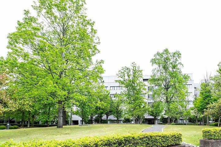 福島県立医科大学の緑豊かなキャンパス風景、ベンチと木々が並ぶ広場。