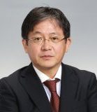 主任教授の永福智志氏のポートレート。ビジネススーツを着用し、真剣な表情でカメラを見つめている。