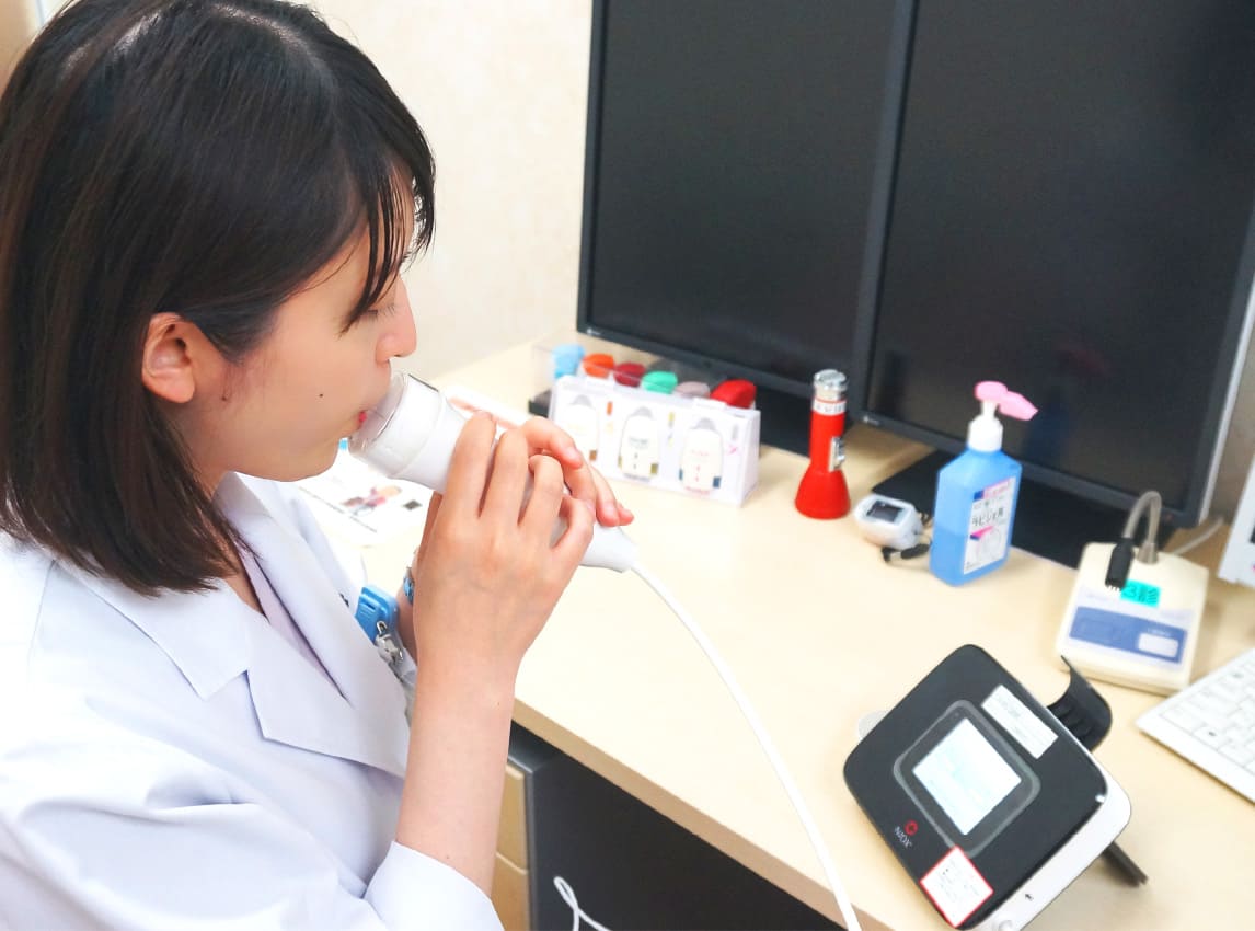 医療従事者が呼気一酸化窒素濃度測定器を使用している様子。喘息の診断に関連する検査を行っています。