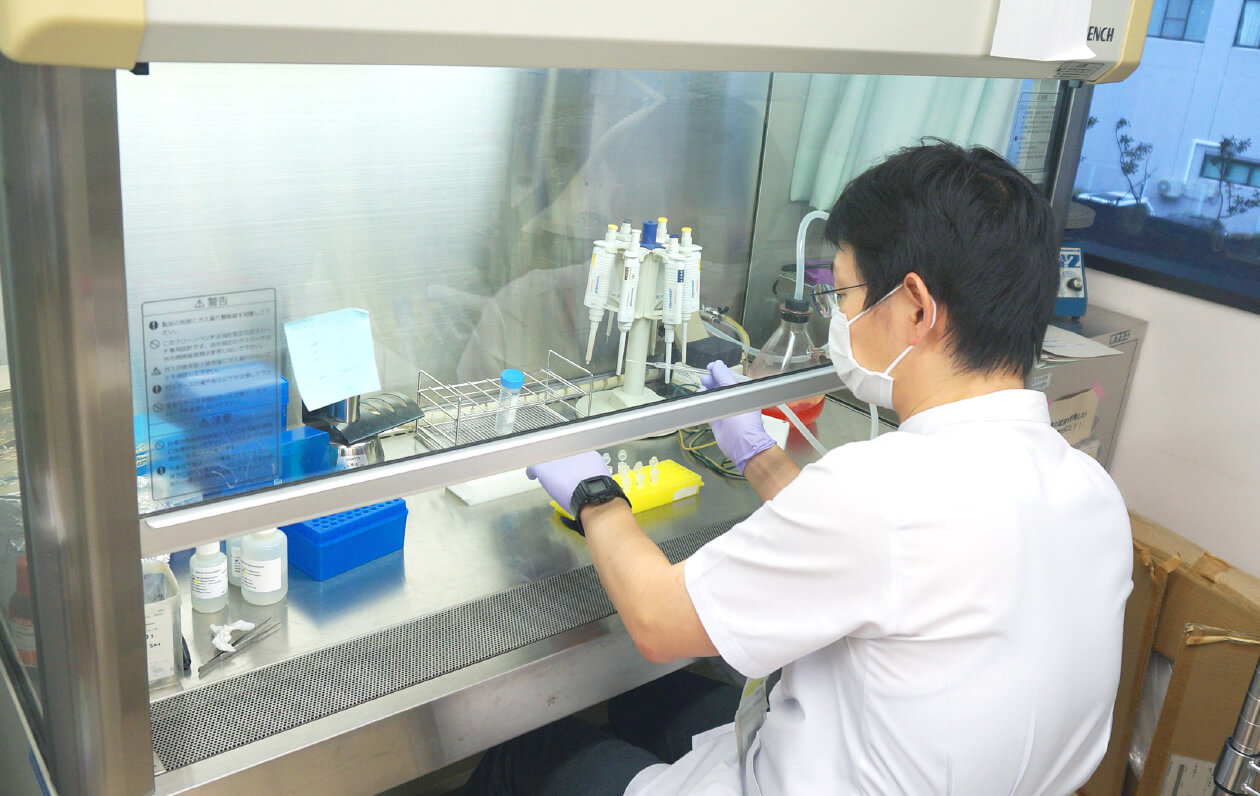 医学生が実験室で器具を使い、研究を行っている様子。安全キャビネット内で作業中。