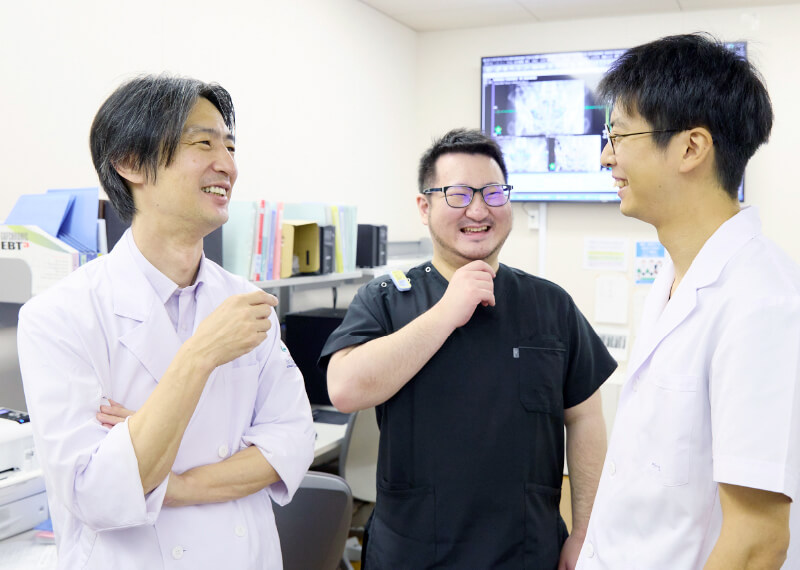 医療現場で笑顔を交わす医師たちが、和やかな雰囲気の中で会話を楽しんでいる様子。