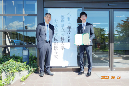 松本聖生先生が福島県立医科大学で学位授与式に出席し、学位証書を持っている様子。