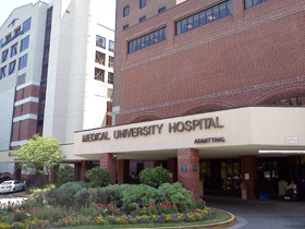 福島県立医科大学病院の外観、入り口には「MEDICAL UNIVERSITY HOSPITAL」の看板が掲げられ、周囲には花壇が整備されています。