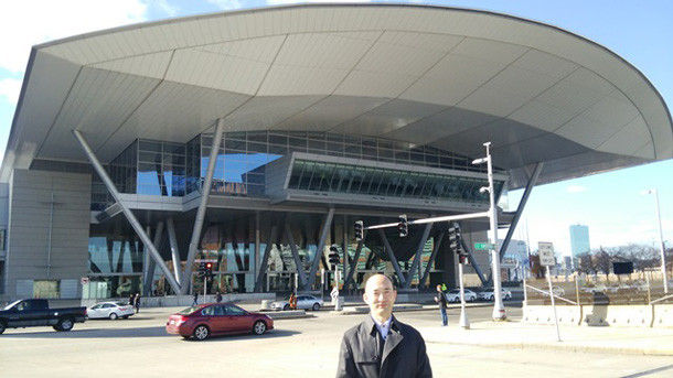 BCEC会場前で撮影された佐藤秀三氏の写真。大きな国際会議場の前に立つ姿。