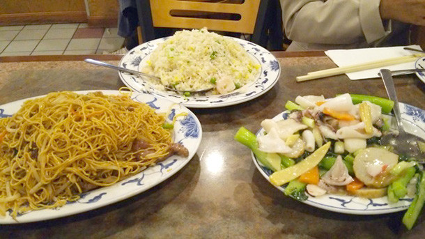 中華街のレストランで提供されるチャーハン、焼きそば、野菜炒めの料理が並んでいる様子。