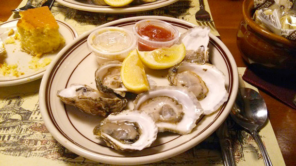 牡蠣とレモン、ソースが添えられた皿の上に盛り付けられた料理の写真。