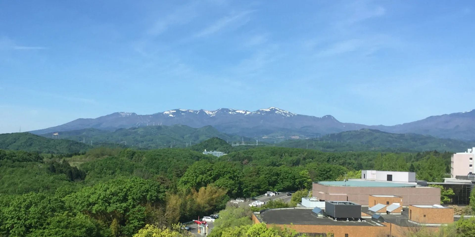 福島県立医科大学のキャンパスから見える緑豊かな山々と青空の風景。