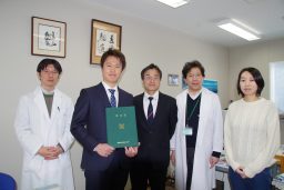 阿左見祐介先生が博士号を取得し、同僚たちと共に記念写真を撮影している様子。