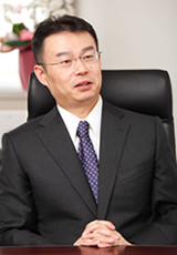 スーツ姿の小島教授が会話をしている様子