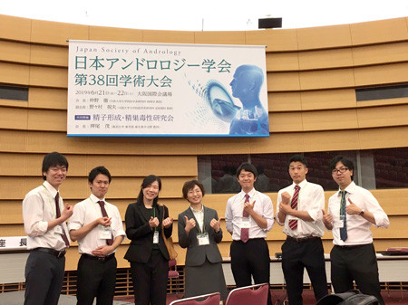 日本アンドロジー学会第38回学術大会の看板の前に立つ7人の人々