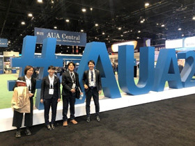 大きな#AUAのサインの前でポーズをとる4人の人々。