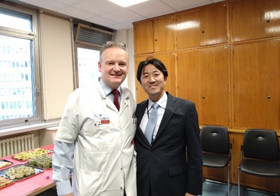 二人の男性が部屋で並んで立っている様子。