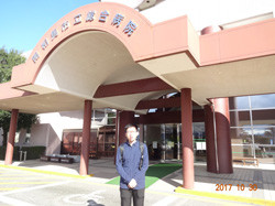 病院の正面玄関前に立つ男性。