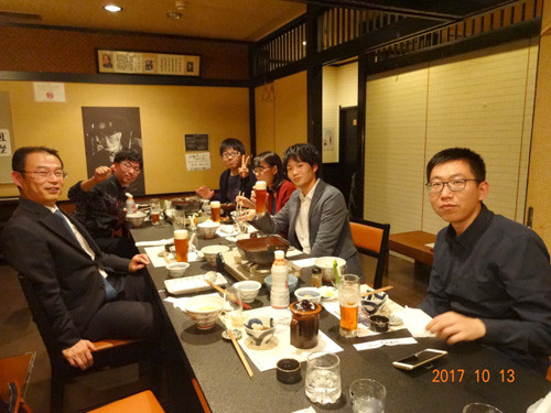 テーブルを囲む6人の男女が笑顔でくつろぎながら飲食を楽しんでいる様子。