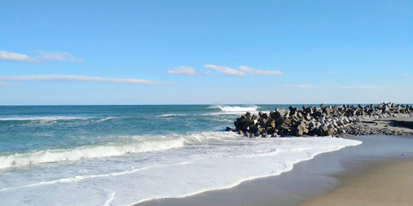 青い空の下、波が押し寄せる美しい海岸の風景。
