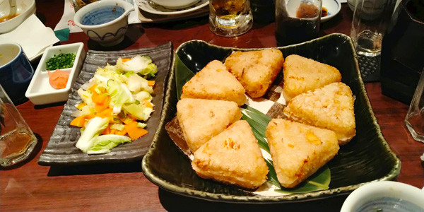 三角形の焼きおにぎりが黒い器に並んでいる様子。