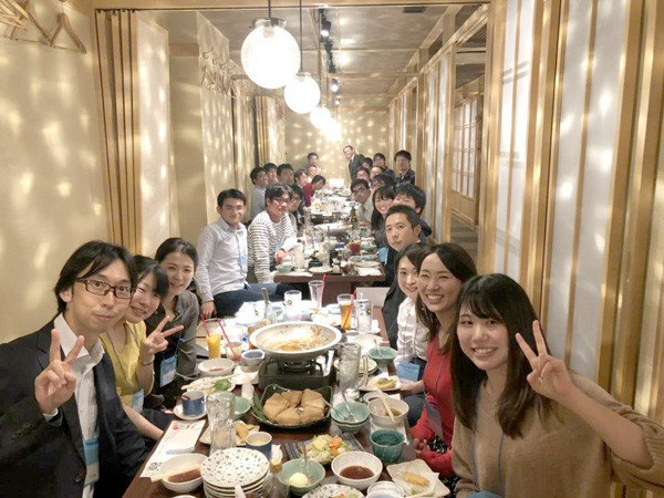 大勢の人々が食卓を囲み、楽しそうにしている様子。