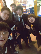 5人が夜の街中で親しげにポーズを取っている様子。