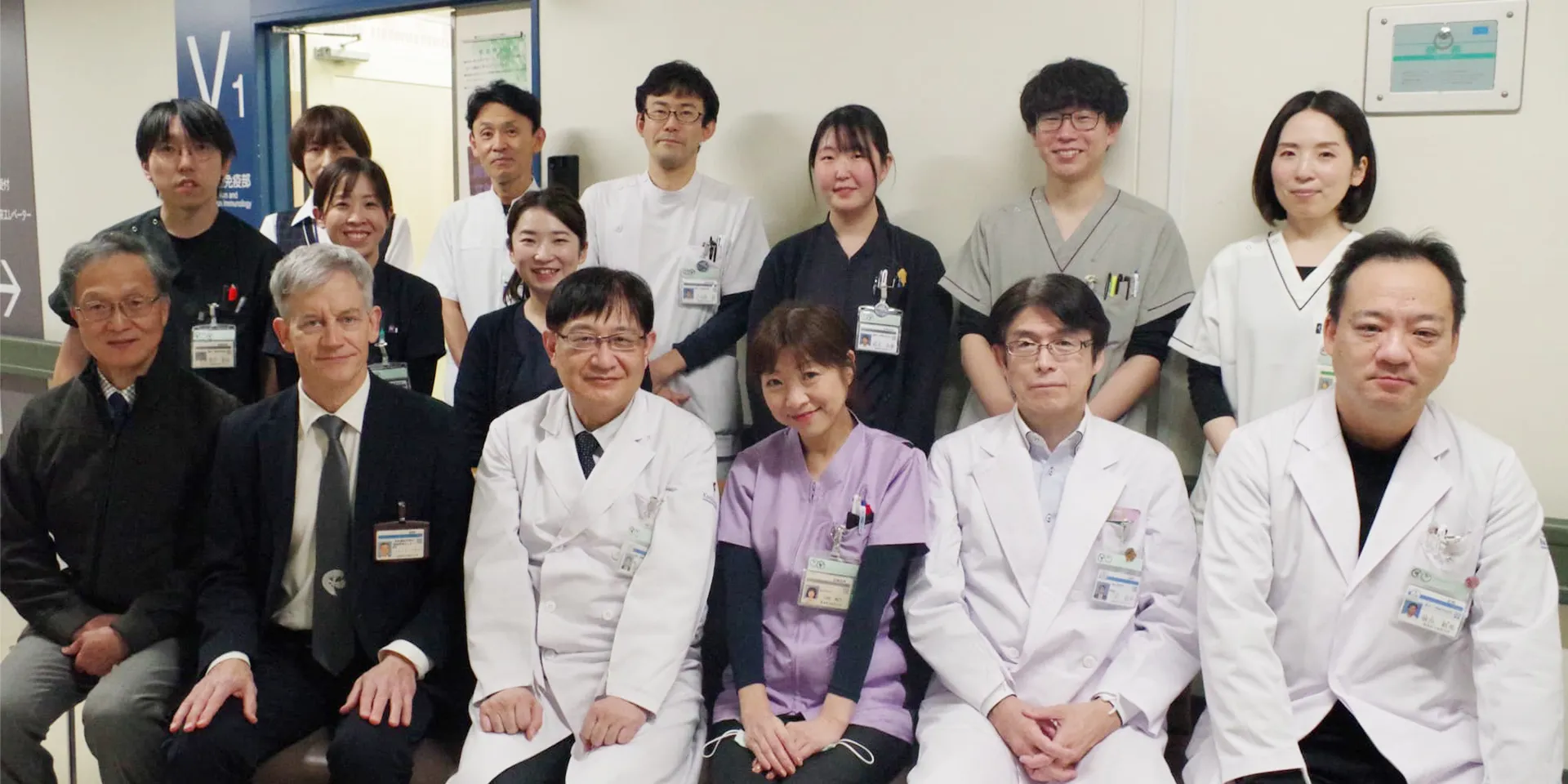 福島県立医科大学の医療スタッフが集合した写真。前列には白衣を着た医師たちが座り、後列には看護師や医療従事者が立っている。