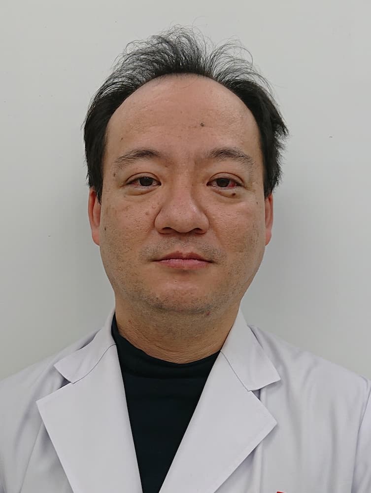 福島県立医科大学の植田航希講師のポートレート。白衣を着用し、真剣な表情でカメラを見つめています。