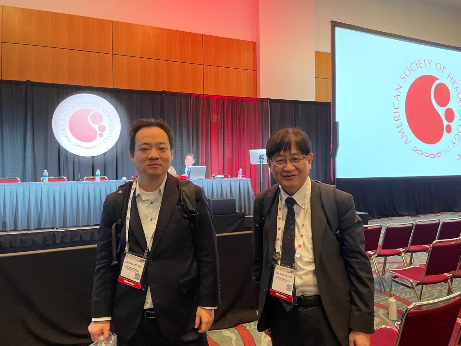 米国血液学会（ASH）に参加した植田航希講師と池田和彦教授が会場でポーズをとっている様子。