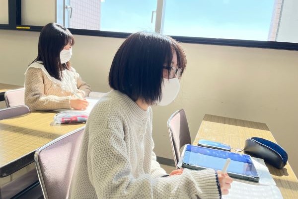 教室でマスクを着用した学生がタブレットを使って学習している様子。