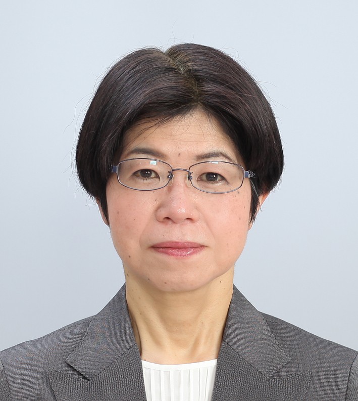 准教授の末永恵子氏がスーツを着て正面を向いているポートレート。背景は淡い色合い。