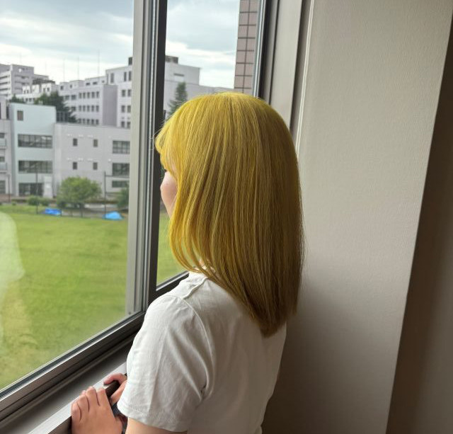 女性が窓辺に立ち外を見つめている様子。