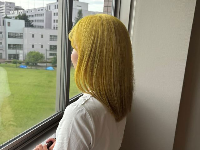 女性が窓辺に立ち外を見つめている様子。