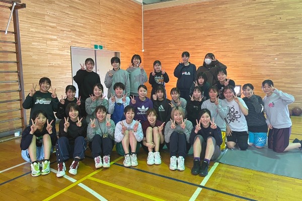 女子バスケットボール部のメンバーが集まり、笑顔でポーズをとっている写真。