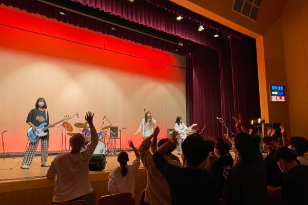 軽音部のライブパフォーマンス中、観客が盛り上がる様子を捉えた写真。