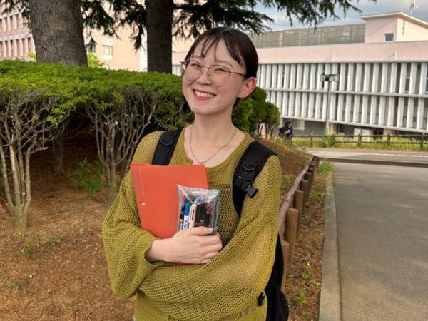 在校生が授業の日に撮影したポートレート。カジュアルな服装で、手にノートや資料を持っている。