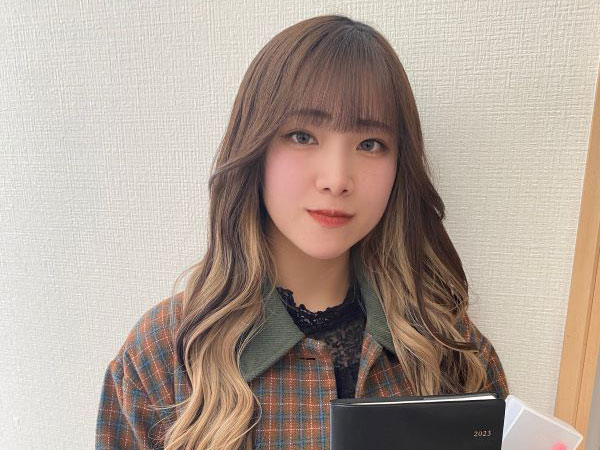 在校生が授業の日に撮影したポートレート。カジュアルな服装で、手にノートや資料を持っている。