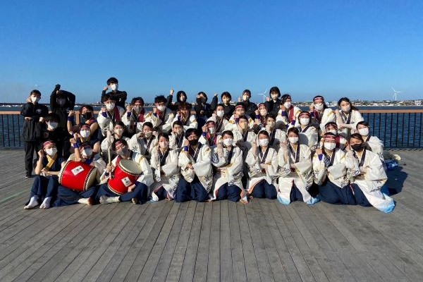 福島県立医科大学の学生たちが、青空の下で集合写真を撮影している様子。伝統的な衣装を着用し、笑顔でポーズを決めている。
