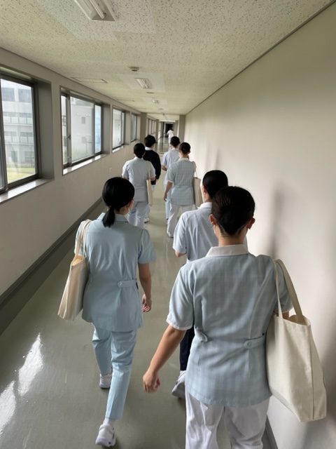 看護学部の学生たちが廊下を歩き、附属病院へ向かう様子。