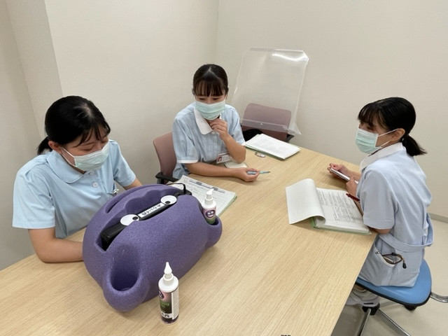 手洗い指導の練習をする医学生たち。紫の機器と手洗い用の蛍光剤を使用。