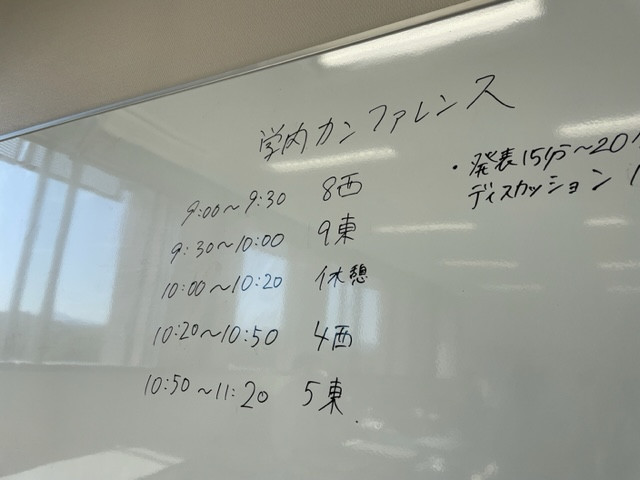 学内カンファレンスのスケジュールがホワイトボードに書かれている様子。