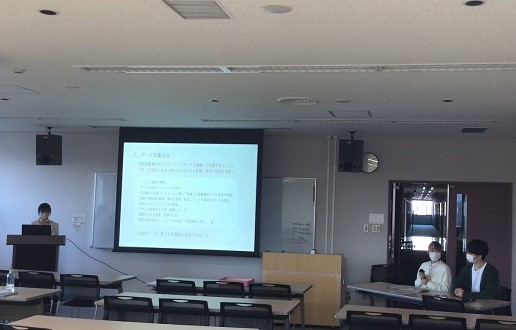 看護研究計画書発表会の様子。プレゼンテーションを行う講演者と聴衆が座る教室の風景。