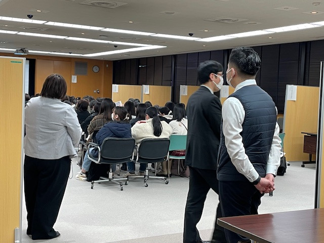 就職ガイダンスの様子。学生たちが講演を受ける中、教育研修支援課のスタッフが見守っています。