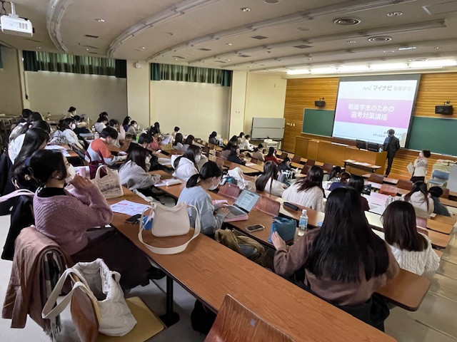 就職セミナーで講義を受ける学生たちが座っている教室の様子。講師が前で説明している。