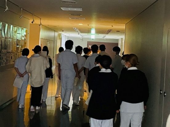 演習室前の廊下で白衣を着た学生たちが待機している様子。