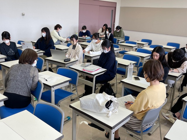 看護学部の教室で、学生たちが統合実習や看護研究について学んでいる様子。