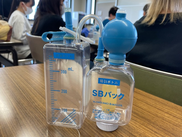 ドレーン管理に使用されるSBバックと計量カップがテーブルに置かれている様子。