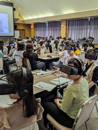 VRゴーグルを装着した学生たちが、認知症体験を行っている様子。講義室でのグループ活動。