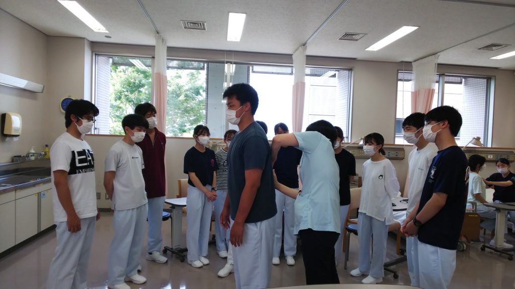 看護技術の授業で、学生たちが打診や聴診の実習を行っている様子。